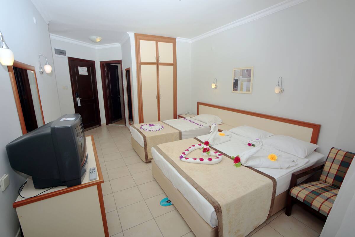 A hotel room with a bed, a desk with a television, and a chair.