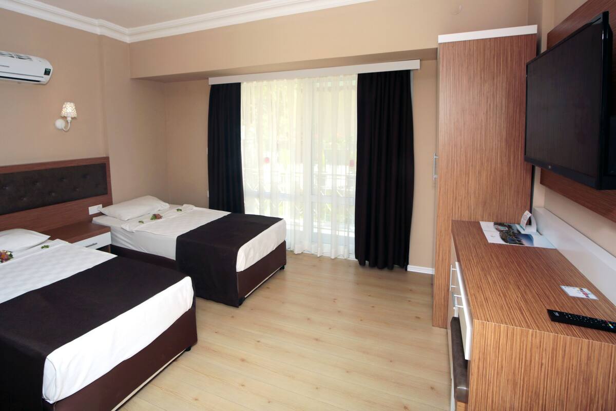A hotel room with two beds, a TV, and an air conditioning unit.