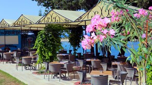 An outdoor cafe with wicker tables and chairs, a covered seating area, and a view of the sea. - Incekum Su Hotel - All Inclusive (Alanya)