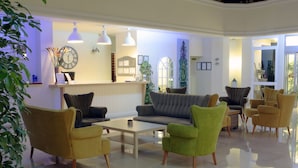A modern lobby with a sofa, armchairs, a coffee table, and a reception desk. - Incekum Su Hotel - All Inclusive (Alanya)