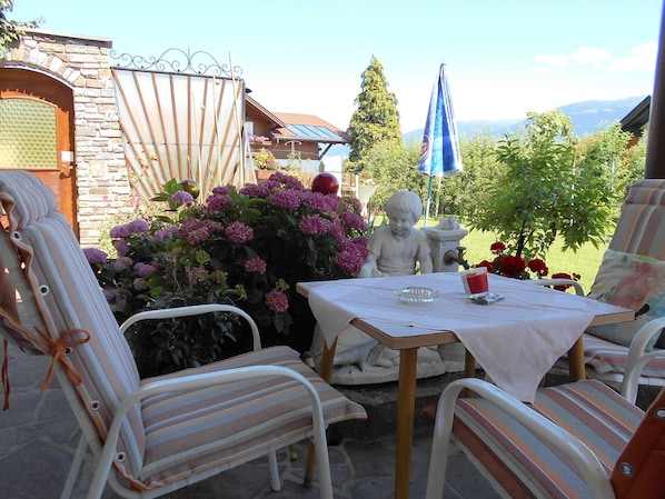 Un patio con una mesa, sillas y una estatua.