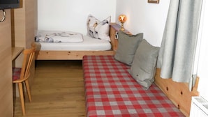 A compact room with a bed, a chair, a desk, and a television.