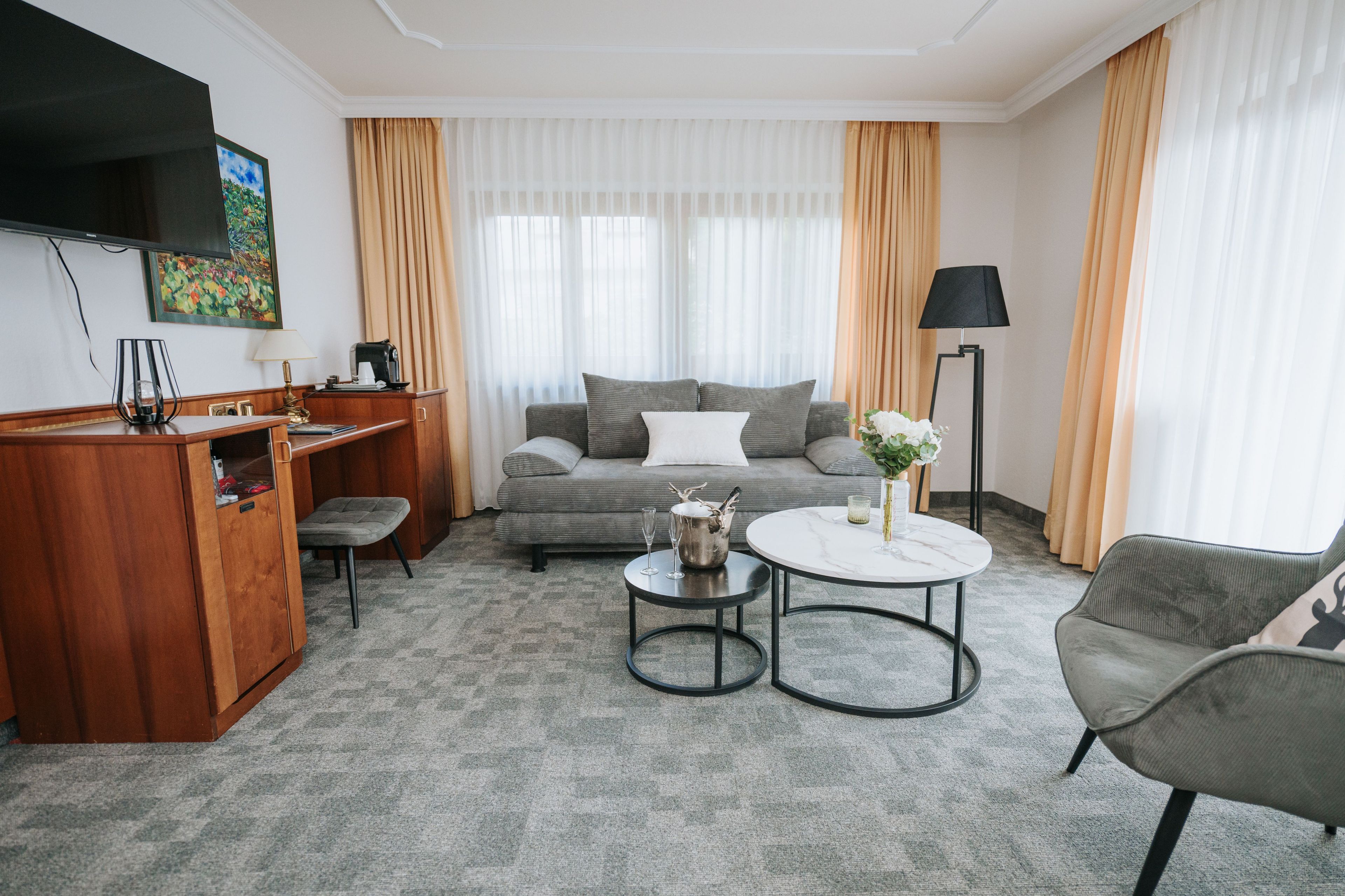 Habitación de hotel con sofá, mesa de centro, televisor, lámpara y escritorio con lámpara.