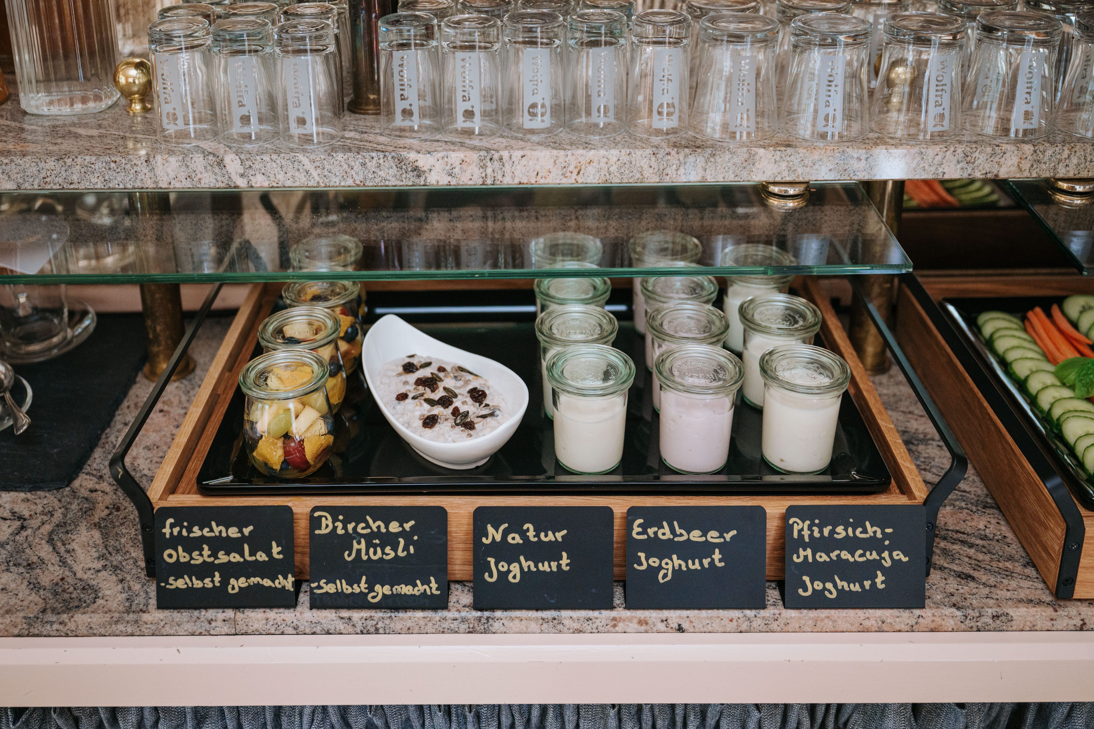 Una exhibición de diversos yogures y productos a base de yogurt en frascos de vidrio con etiquetas, dispuestos sobre una encimera.