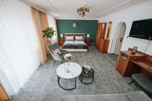 Una habitación de hotel con una cama, un escritorio, una silla, una mesa redonda y un televisor.