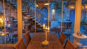 Ein Holzespeisesaal mit sechs Stühlen, einer Kerzenarrangement und Blick auf eine Steintreppe, die in einen Garten führt.