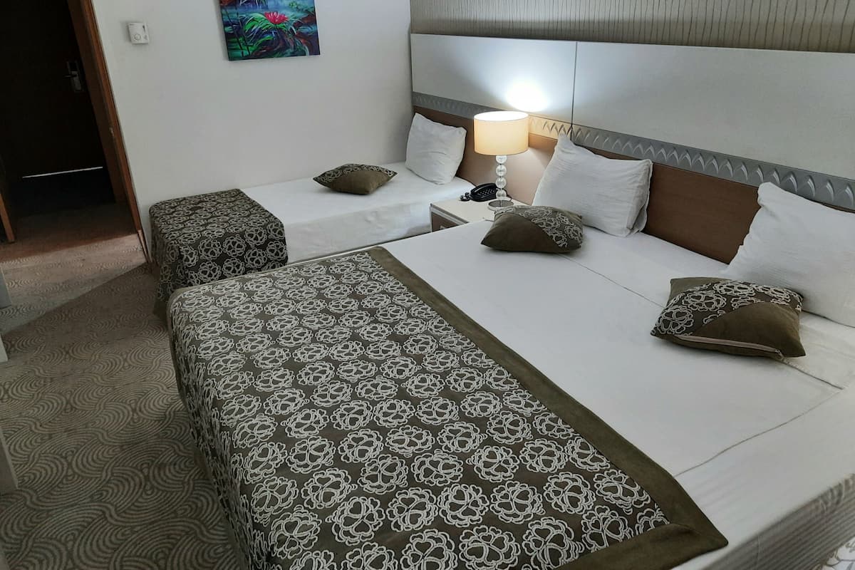 Une chambre d’hôtel avec deux lits, une table de chevet, une lampe et un tableau au mur.