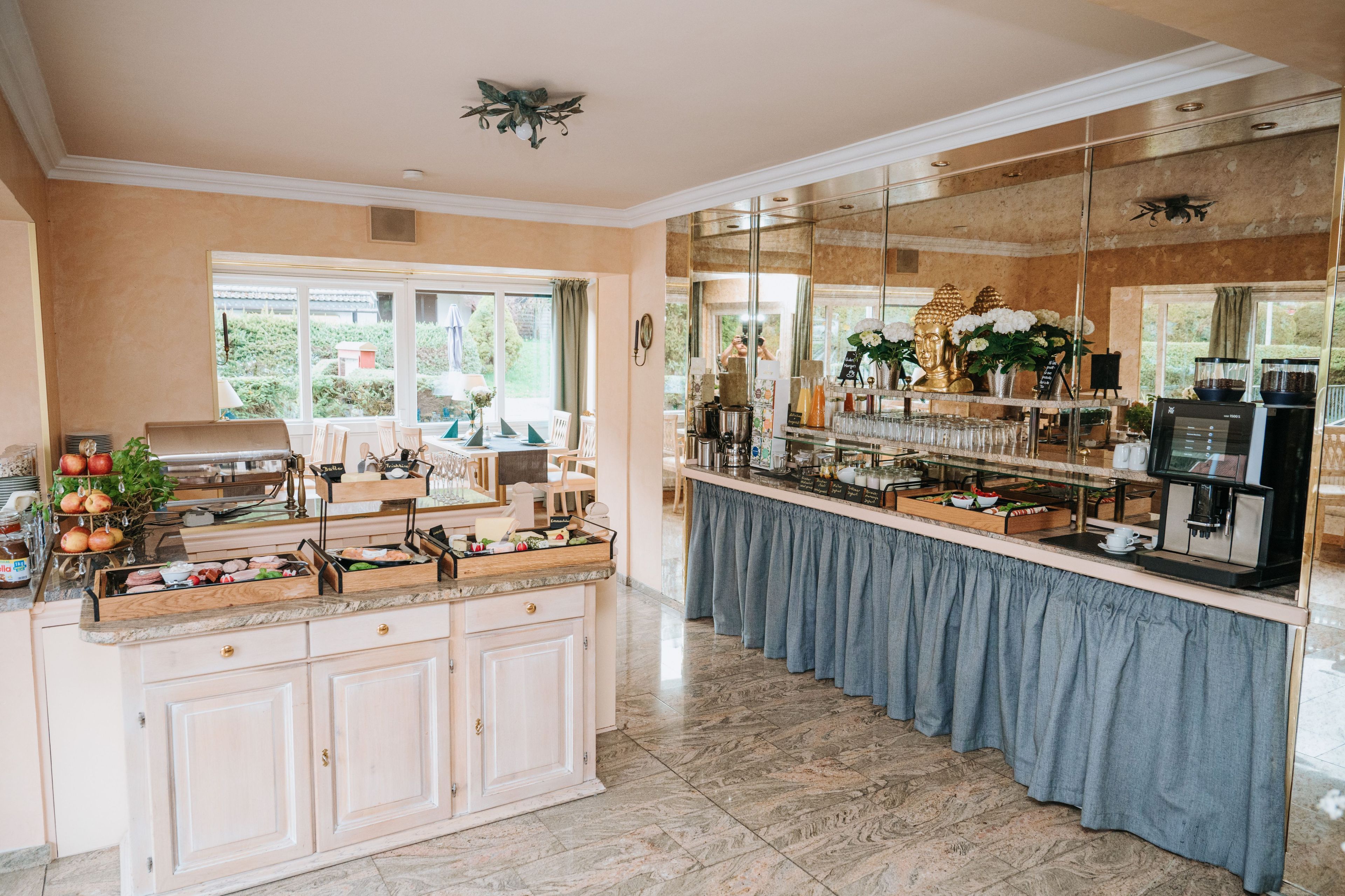A kitchen with a marble countertop, a coffee station, and a view of the outdoors.