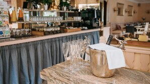 A bar area with a marble countertop, a silver pitcher with a white napkin, and several empty glasses.