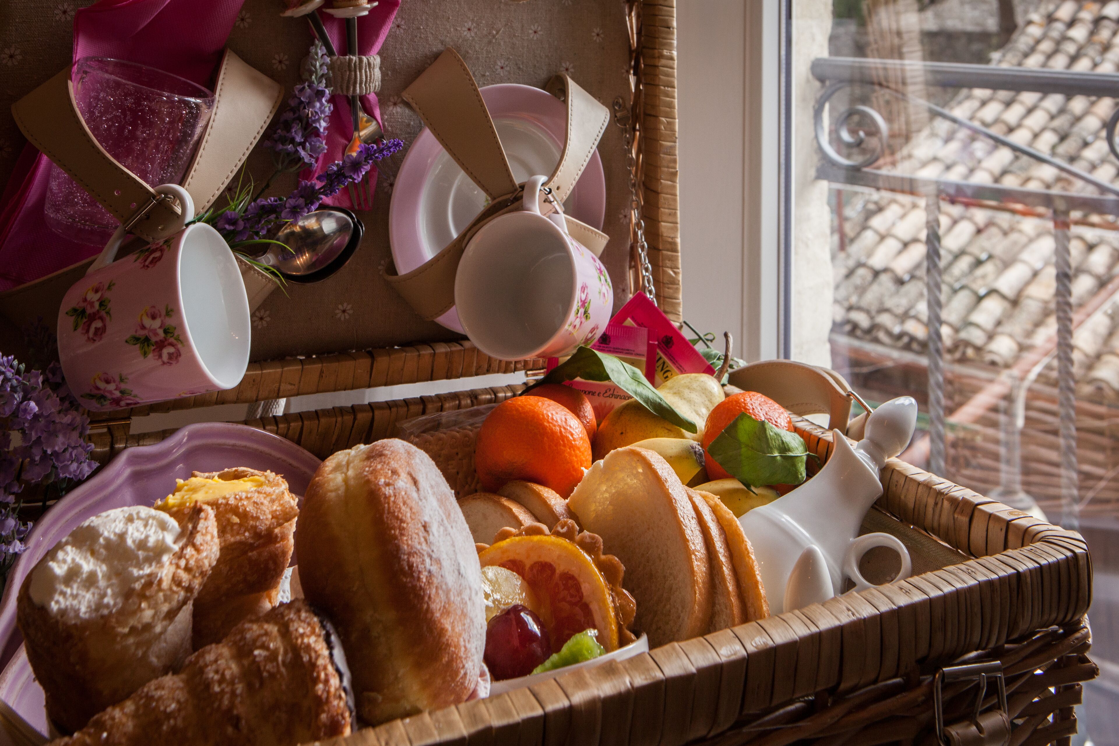 A wicker basket filled with pastries, fruits, and a teapot.