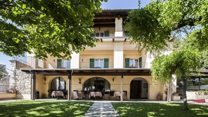 A two-story building with a covered patio area, outdoor seating, and a gravel path leading to the entrance. - Hotel Ideale (Assisi)