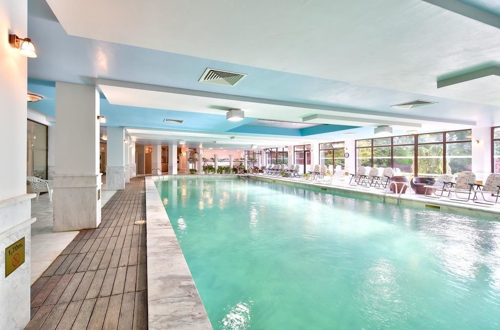 Una piscina techada, una piscina al aire libre, sombrillas