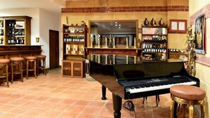 Een bar met een piano, krukken, flessen op planken en een bakstenen muur.