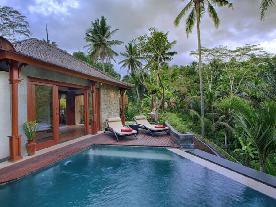 A poolside area with lounge chairs and a stone building with a tiled roof.