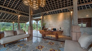 A spacious room with a large wooden table, a sofa, and a patterned floor. - Nau Villa Ubud (Sebatu)