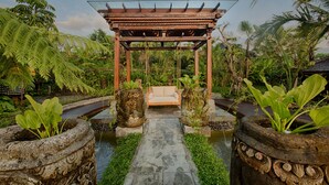 A garden with a wooden swing set and a stone pathway leading to a gazebo. - Nau Villa Ubud (Sebatu)