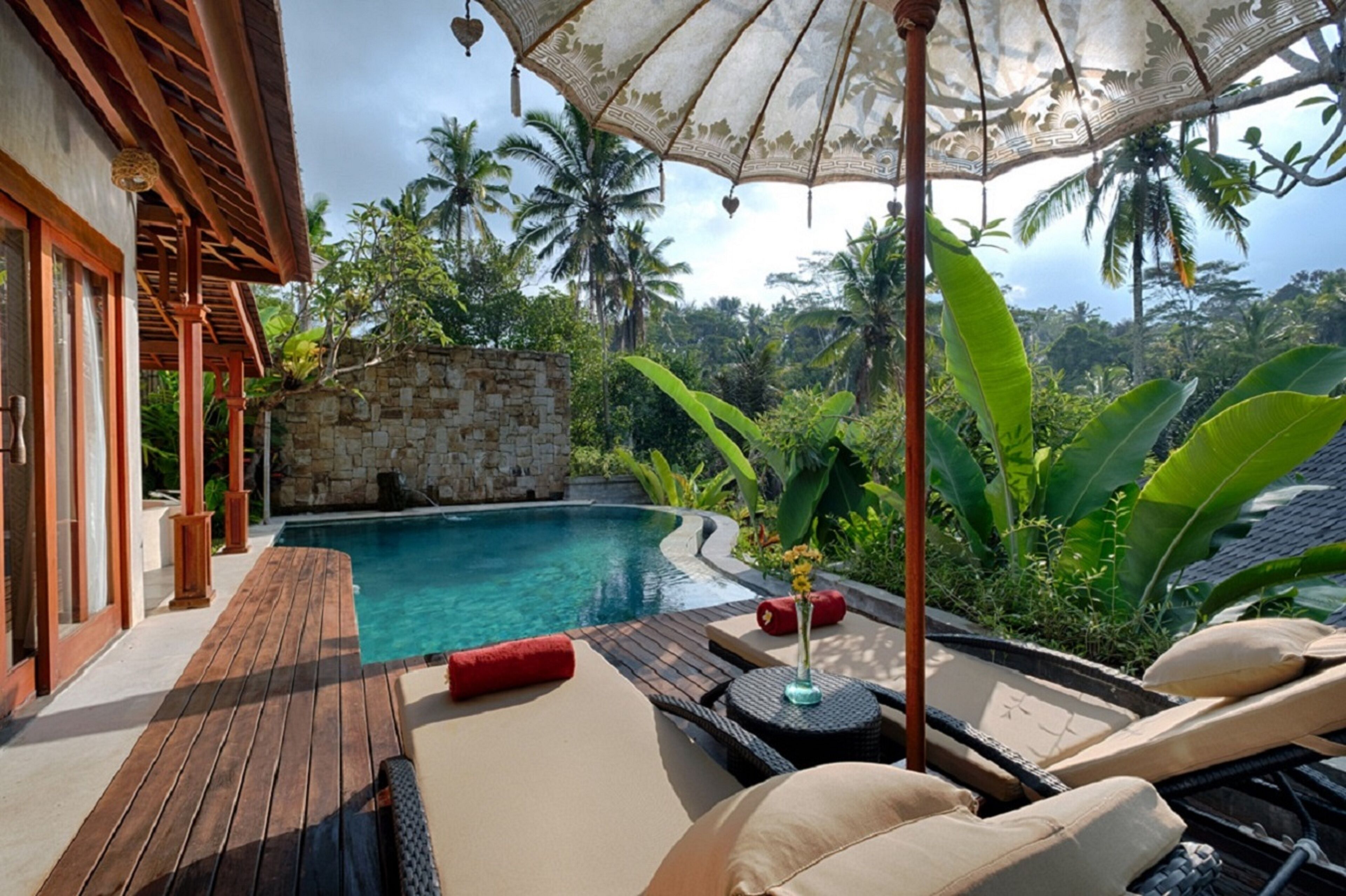 A poolside area with wooden decking, lounge chairs, and a canopy.