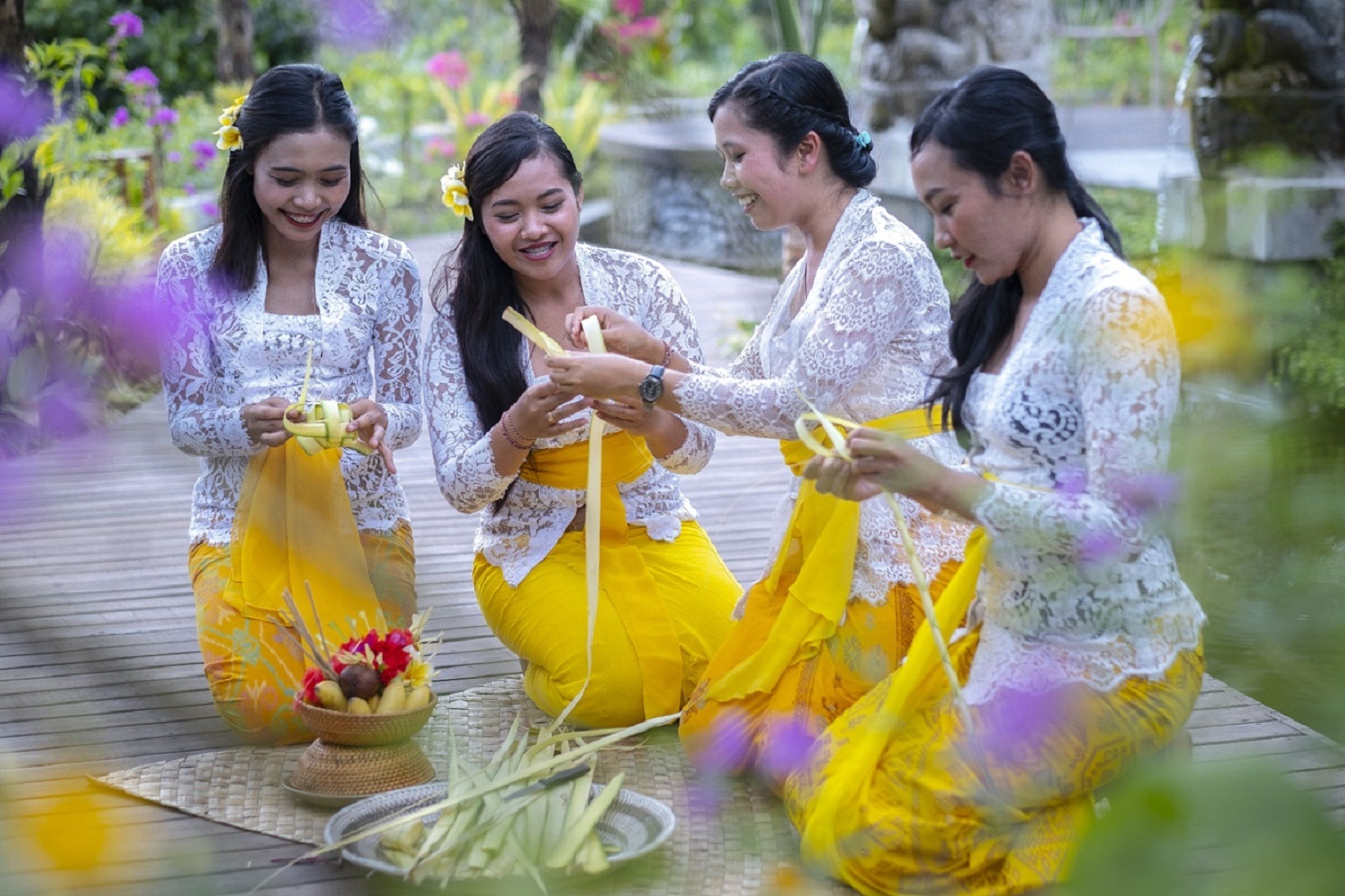 Tres mujeres vestidas con ropa tradicional sentadas en una cubierta de madera al aire libre.