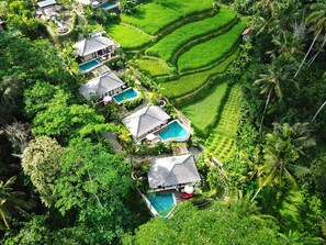 A resort with multiple pools, lush green terraced fields, and traditional-style buildings.