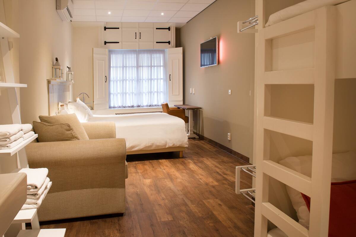 Ein Hotelzimmer mit Bett, einer Couch, einem kleinen Tisch und einem Fernseher an der Wand.