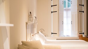 A hotel room with a bed, a bedside table with a lamp, a window with curtains, and a view of the outside. - Hotel Jo van den Bosch ('s-Hertogenbosch)