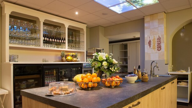 A kitchen with a bar area, featuring glassware, bottles, and fresh produce on the counter. - Hotel Jo van den Bosch ('s-Hertogenbosch)