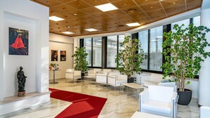 A modern lobby with white furniture, large windows, and indoor plants. - Prealpi Hotel (San Vendemiano)