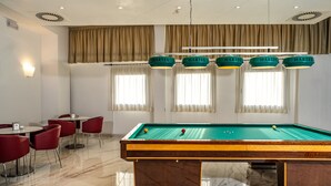 A pool table with a green felt surface, surrounded by red chairs and a white table. - Prealpi Hotel (San Vendemiano)