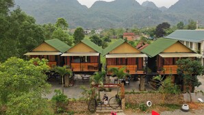Une rangée de cabanes en bois aux toits verts, entourées d’une végétation luxuriante et avec des montagnes en arrière-plan.