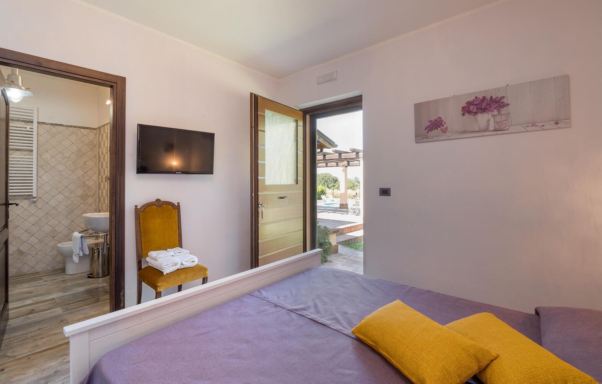 Une chambre avec un lit, une chaise sur laquelle sont posées des serviettes, une télévision et une vue sur l’extérieur.