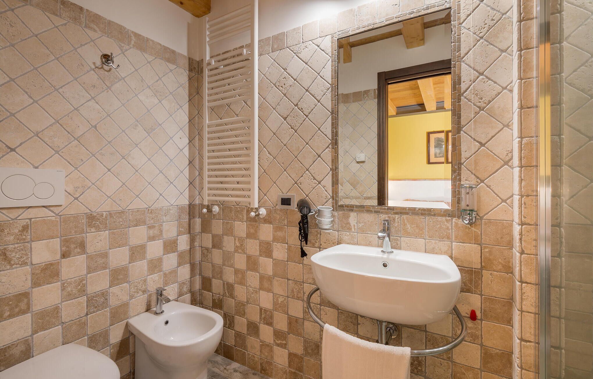 A bathroom with a bidet, a sink, and a mirror.