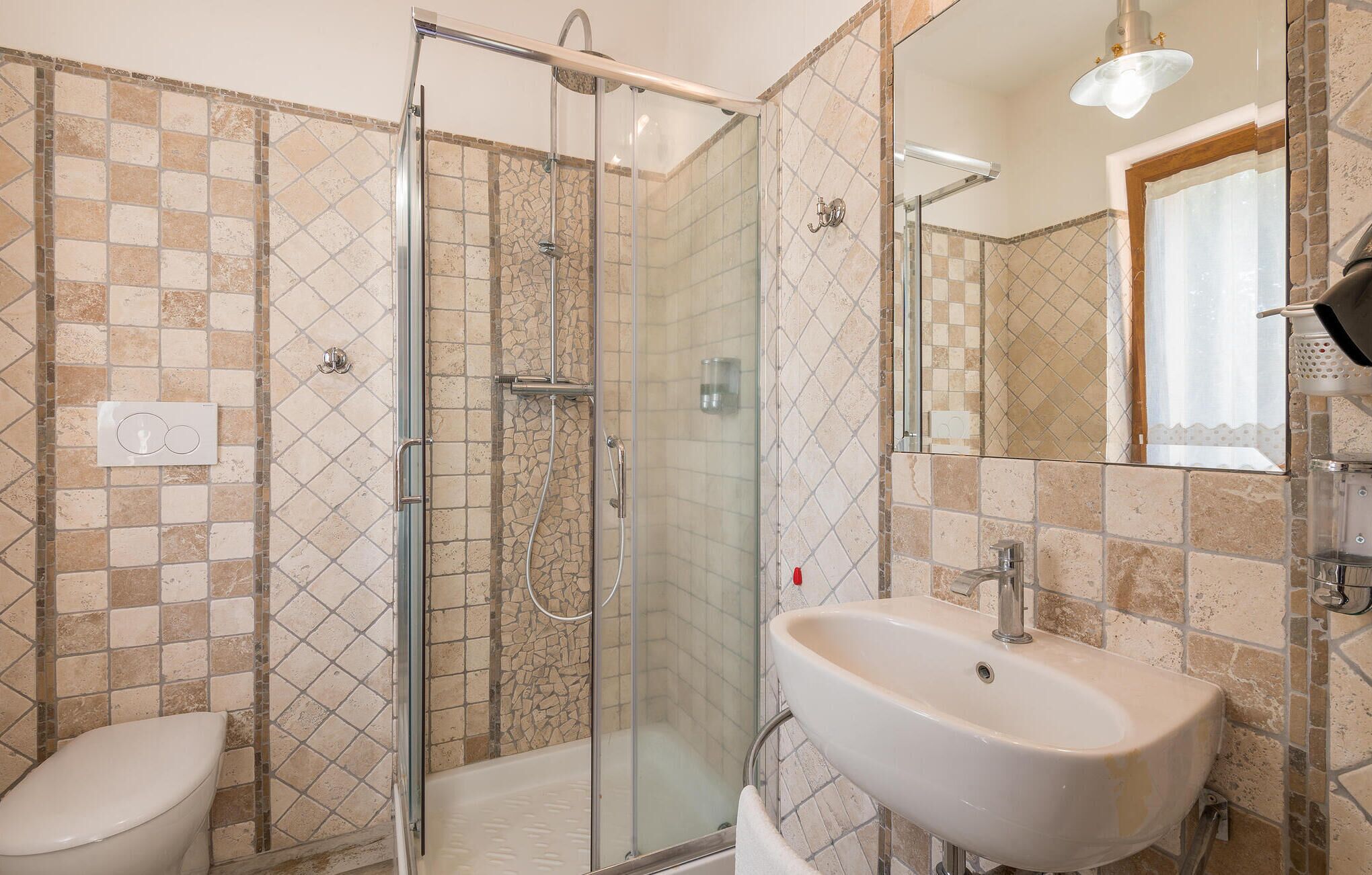 Une salle de bain avec une douche à parois de verre, un lavabo blanc et des toilettes.
