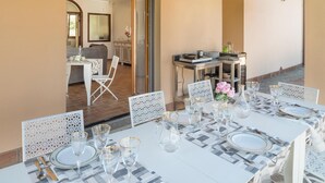 A dining area with a table set for six, featuring white chairs with intricate cut-out patterns. - Awesome home in Capodimonte (VT) (Capodimonte (VT))