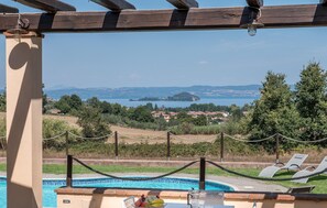 Un espace piscine offrant une vue sur un lac et des collines lointaines.