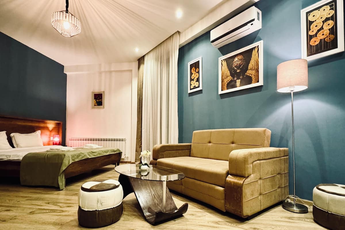 A modern hotel room with a bed, a sofa, a coffee table, and a floor lamp.