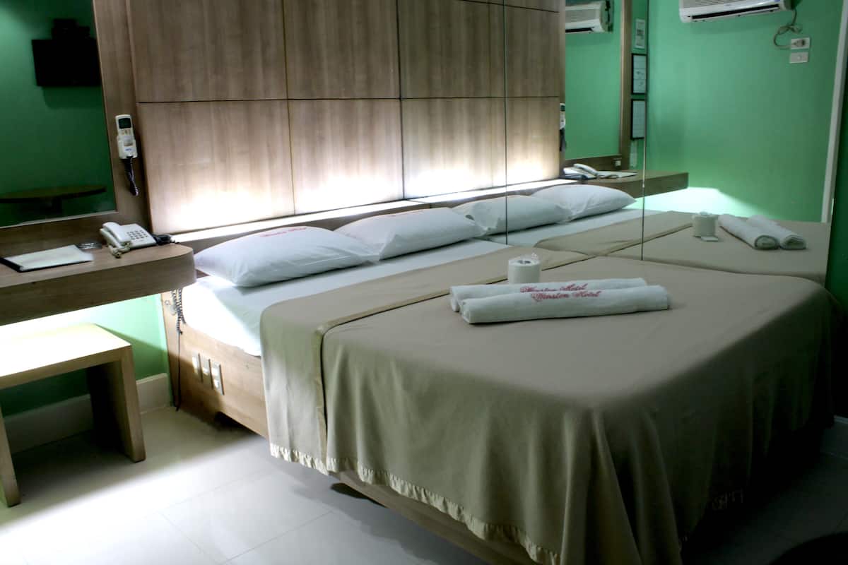Una habitación de hotel con cama, mesita de noche y espejo.