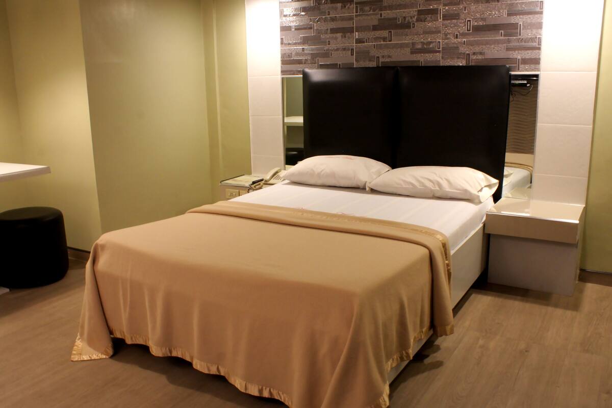 Una habitación de hotel con cama, mesita de noche y teléfono.