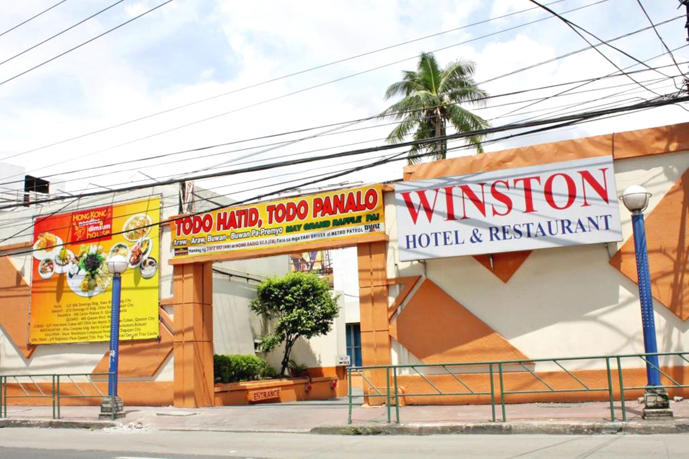 A hotel entrance with a sign for Winston Hotel & Restaurant and a nearby food advertisement.