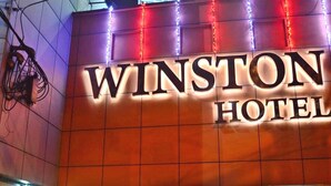 Et skilt for Winston Hotel med oplyste bogstaver og dekorativ belysning.