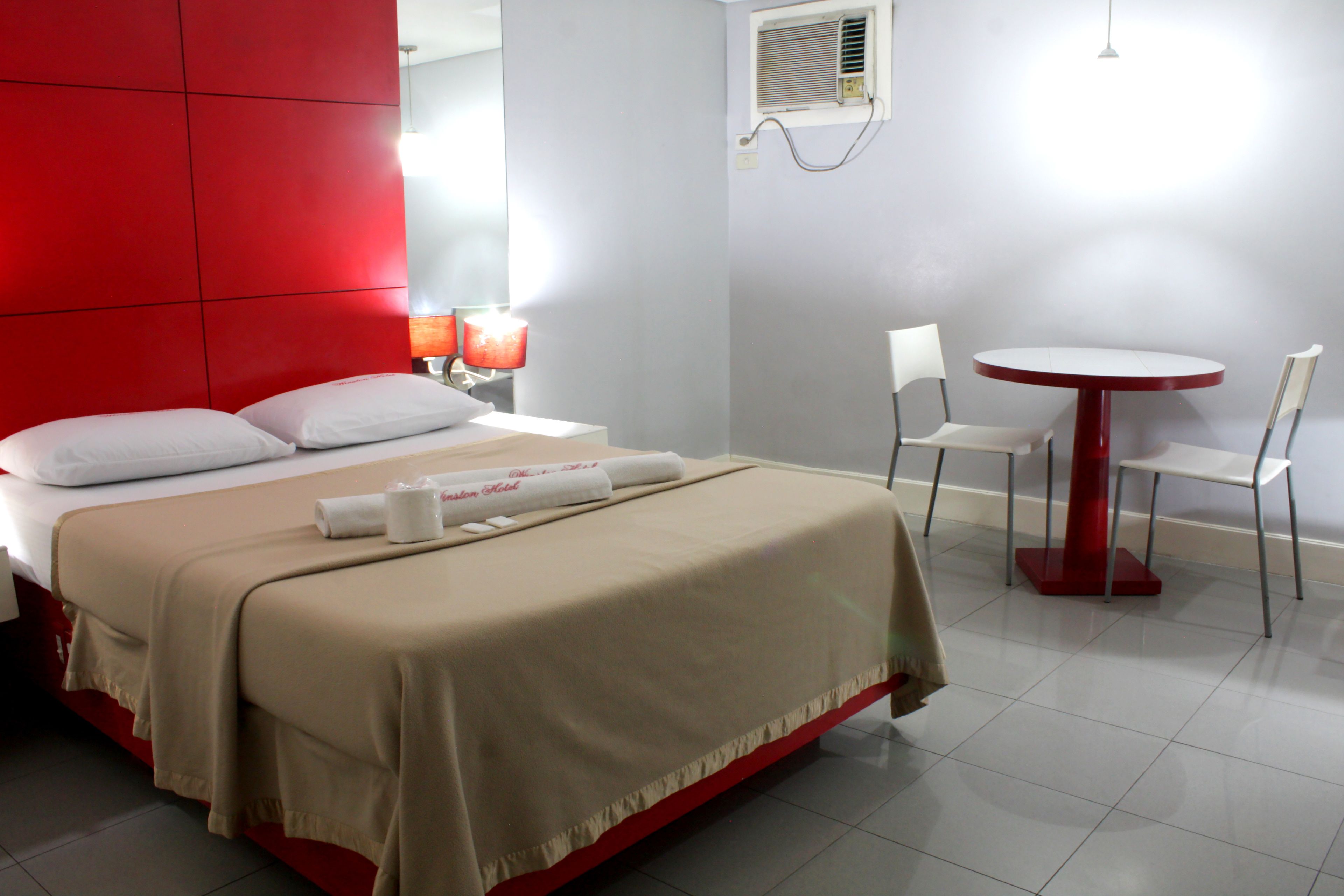 A hotel room with a bed, a table, and two chairs.
