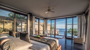 Un dormitorio amplio con una cama grande, un escritorio y vista al océano.