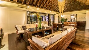 Un salón amplio con techo de madera, un comedor y una cocina visibles a través de un arco.