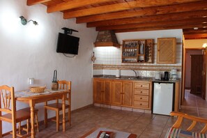 Una cocina con gabinetes de madera, salpicadero de azulejos, un lavamanos y un refrigerador.