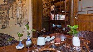 A traditional room with a wooden table, vases, and a bookshelf. - Demen Renli Hotel (Chengdu)