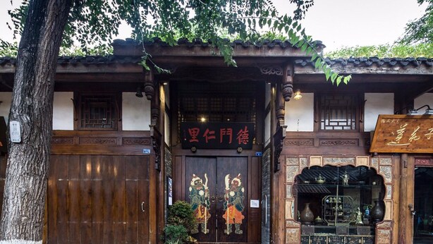 A traditional wooden building with a large wooden door featuring intricate carvings and a sign above it. - Demen Renli Hotel (Chengdu)