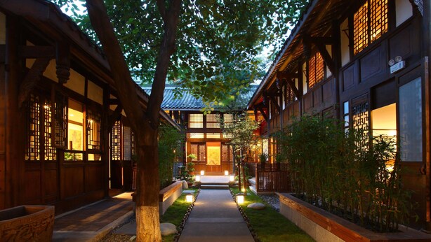 A traditional Japanese-style building with a central pathway leading to a main entrance, surrounded by wooden structures and greenery. - Demen Renli Hotel (Chengdu)