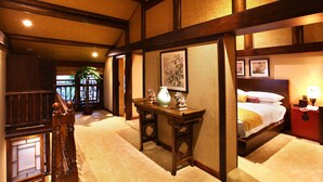 A traditional Japanese-style room with tatami flooring, a low wooden table with a vase, a bed with a yellow blanket, and a red nightstand. - Demen Renli Hotel (Chengdu)