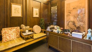 A reception area with a wooden bench, framed artwork, a printer, and a decorative vase. - Demen Renli Hotel (Chengdu)