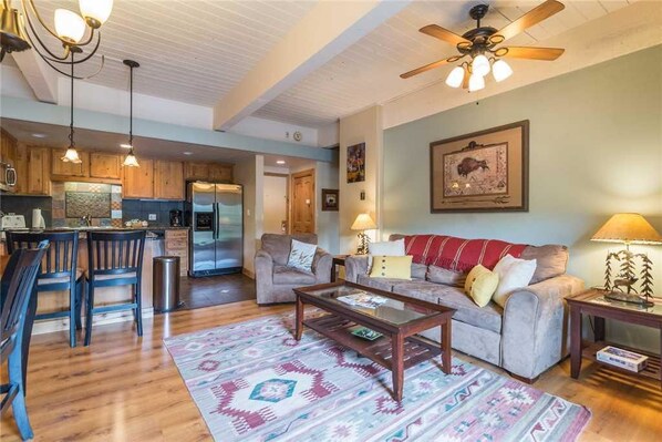 A spacious living area with a wooden floor, a sofa, a coffee table, and a ceiling fan.