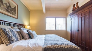 Une chambre à coucher avec un lit, une fenêtre et une armoire en bois.